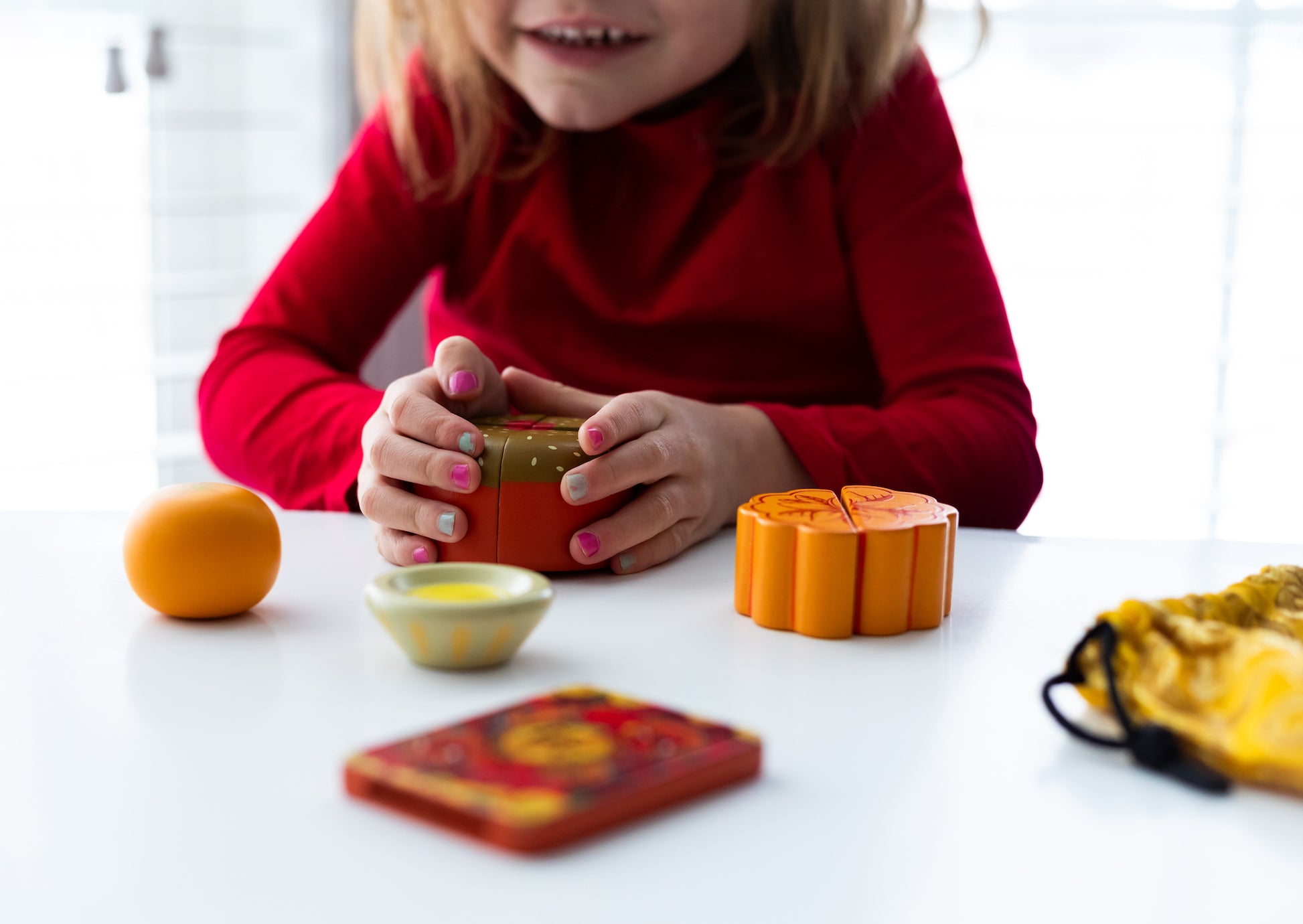 Child in red playing with 4-piece gau and other lucky tummy play food at a table