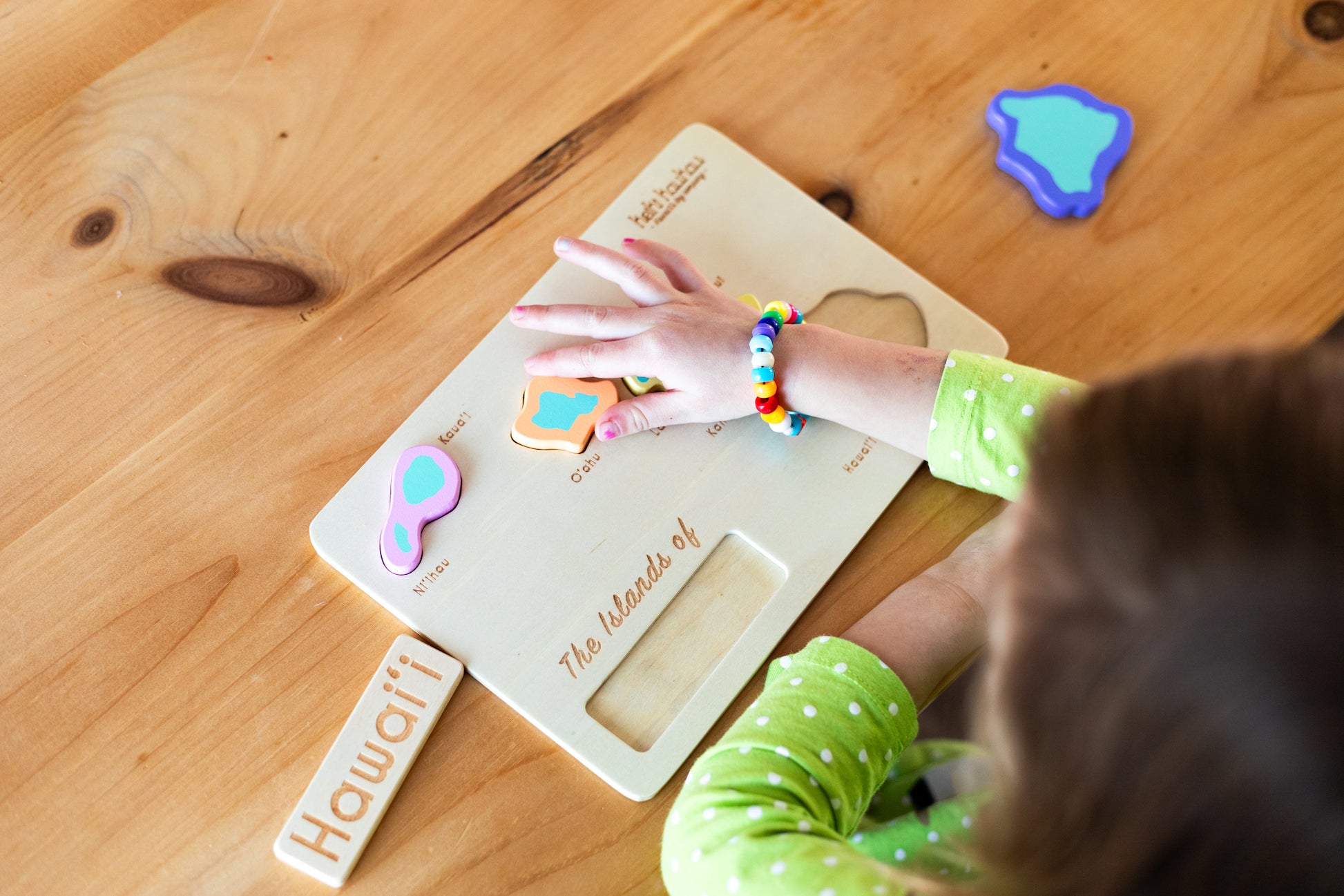 Child placing Oahu puzzle piece into the Hawaiian island puzzle