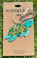 Load image into Gallery viewer, Turtle-shaped keychain on a brown card with &#39;Aloha Land&#39; branding, displayed on grass.