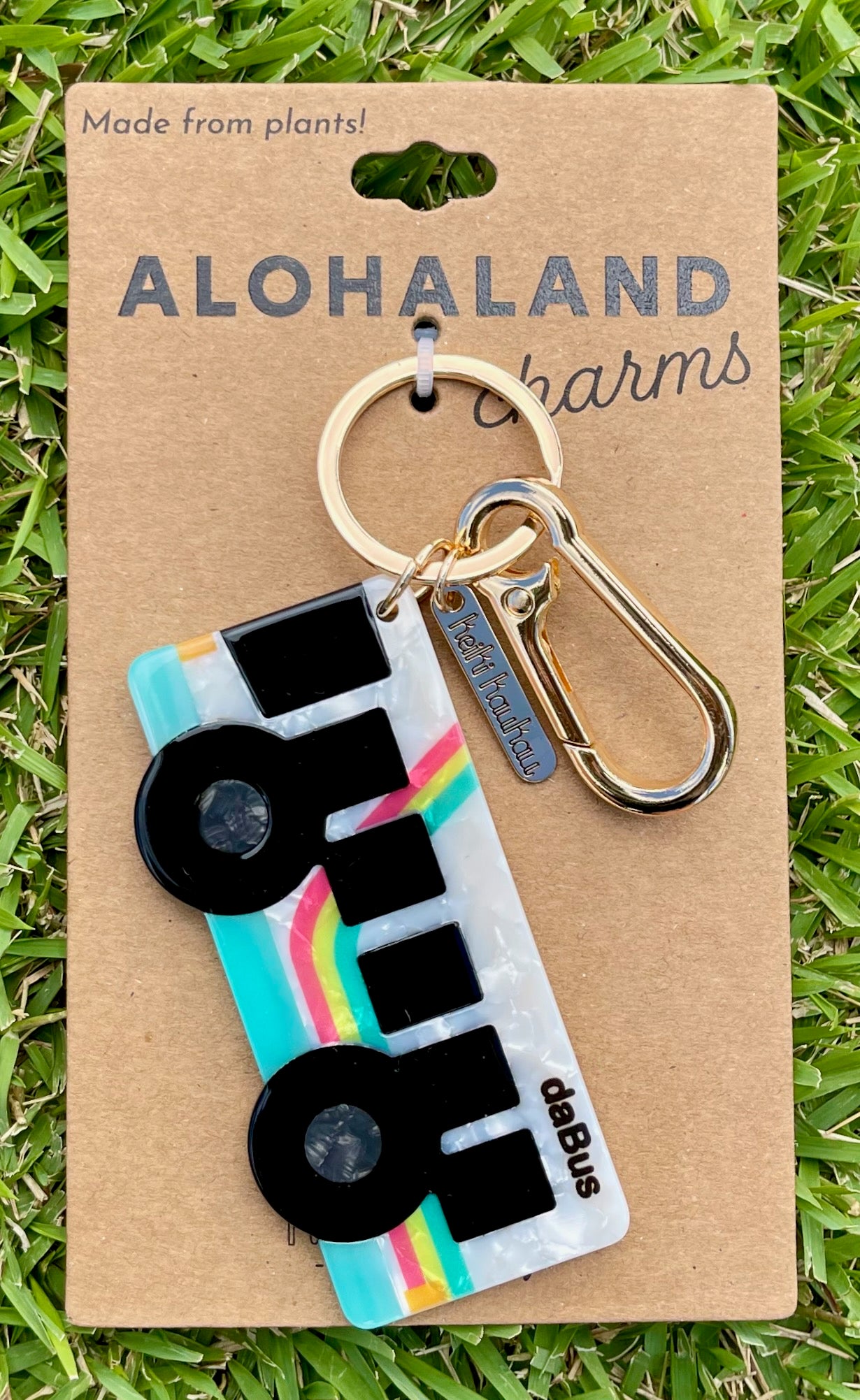 Keychain with colorful Bus design on a 'Alohaland Charms' card in grass
