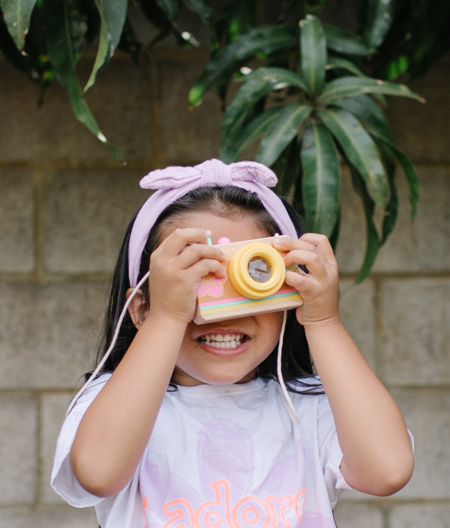 Little girl looking through the kaleidescopic lens of the wooden camera
