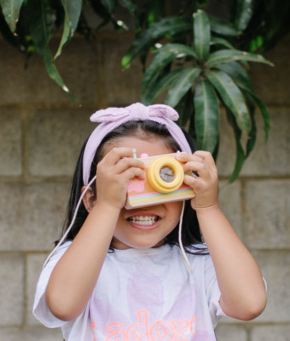 Little girl looking through the kaleidescopic lens of the wooden camera