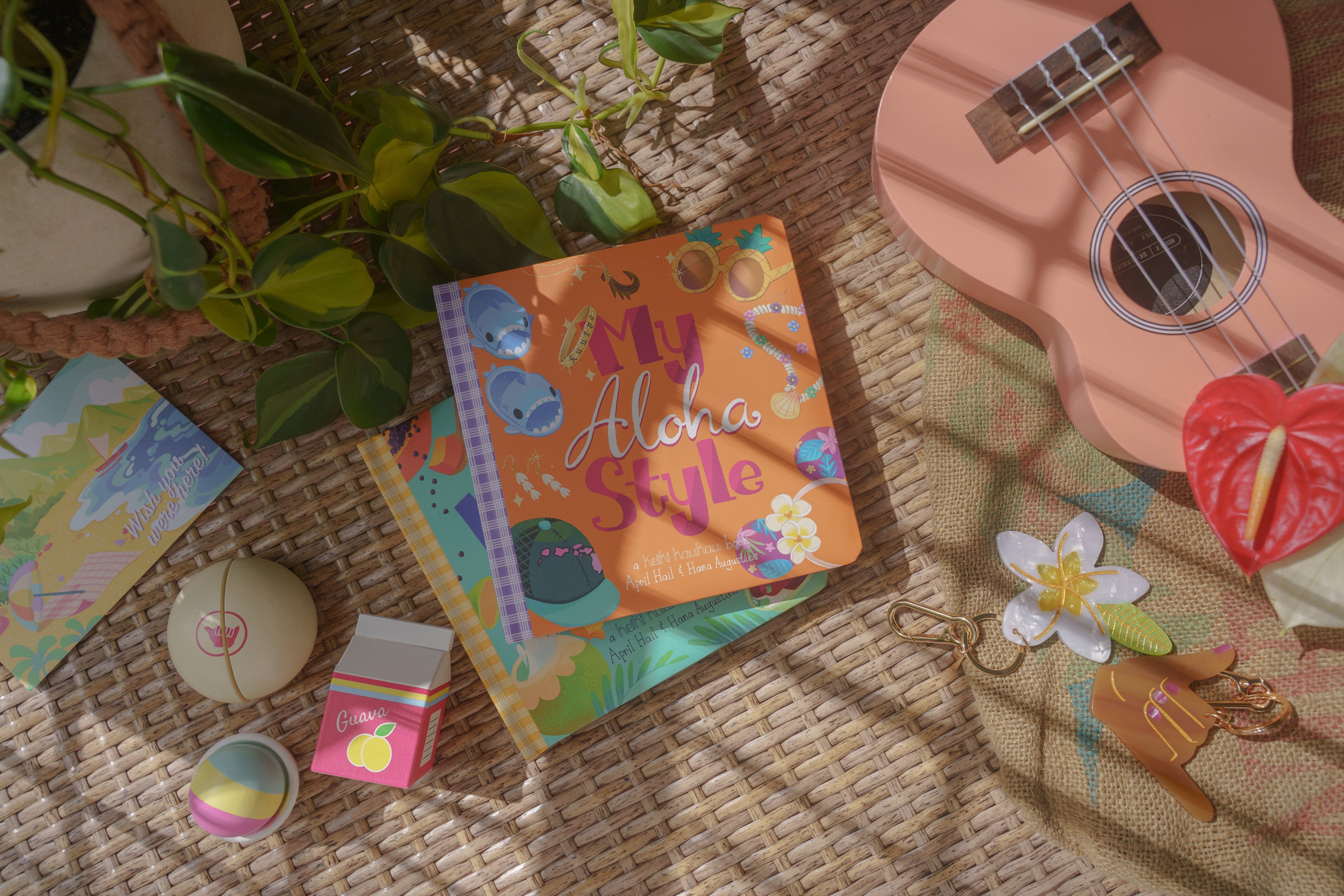 Colorful book titled 'My Aloha Style' with a ukulele and decorative items on a woven surface.