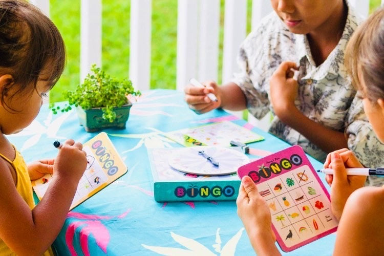two girls and a little boy checking things off their bingo cards with erasable markers