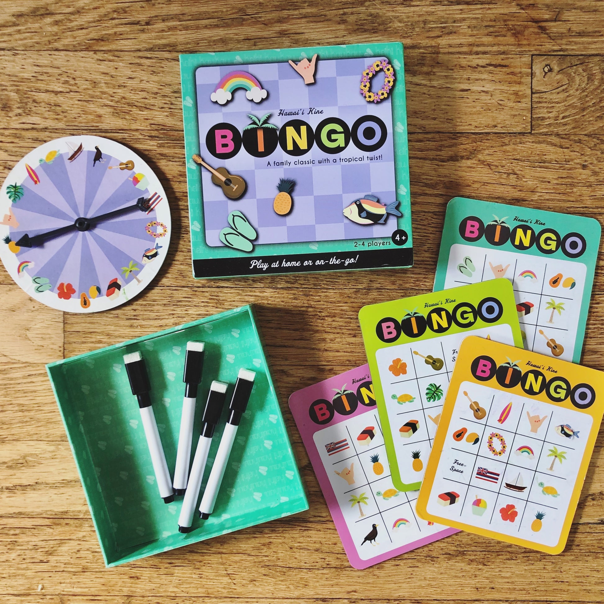 Teal and purple checkered box reading "BINGO" next to bingo cards, spinning wheel, and erasable markers