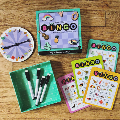 Teal and purple checkered box reading "BINGO" next to bingo cards, spinning wheel, and erasable markers
