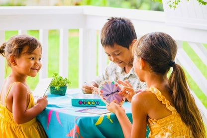 two girls and a boy playing with the bingo game at a table