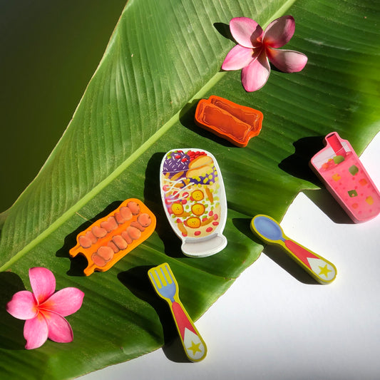 6 Filipino food shaped puzzle pieces (barbecue, holo-holo, lumpia, a pink drink, a fork, and a spoon) on a tea leaf 