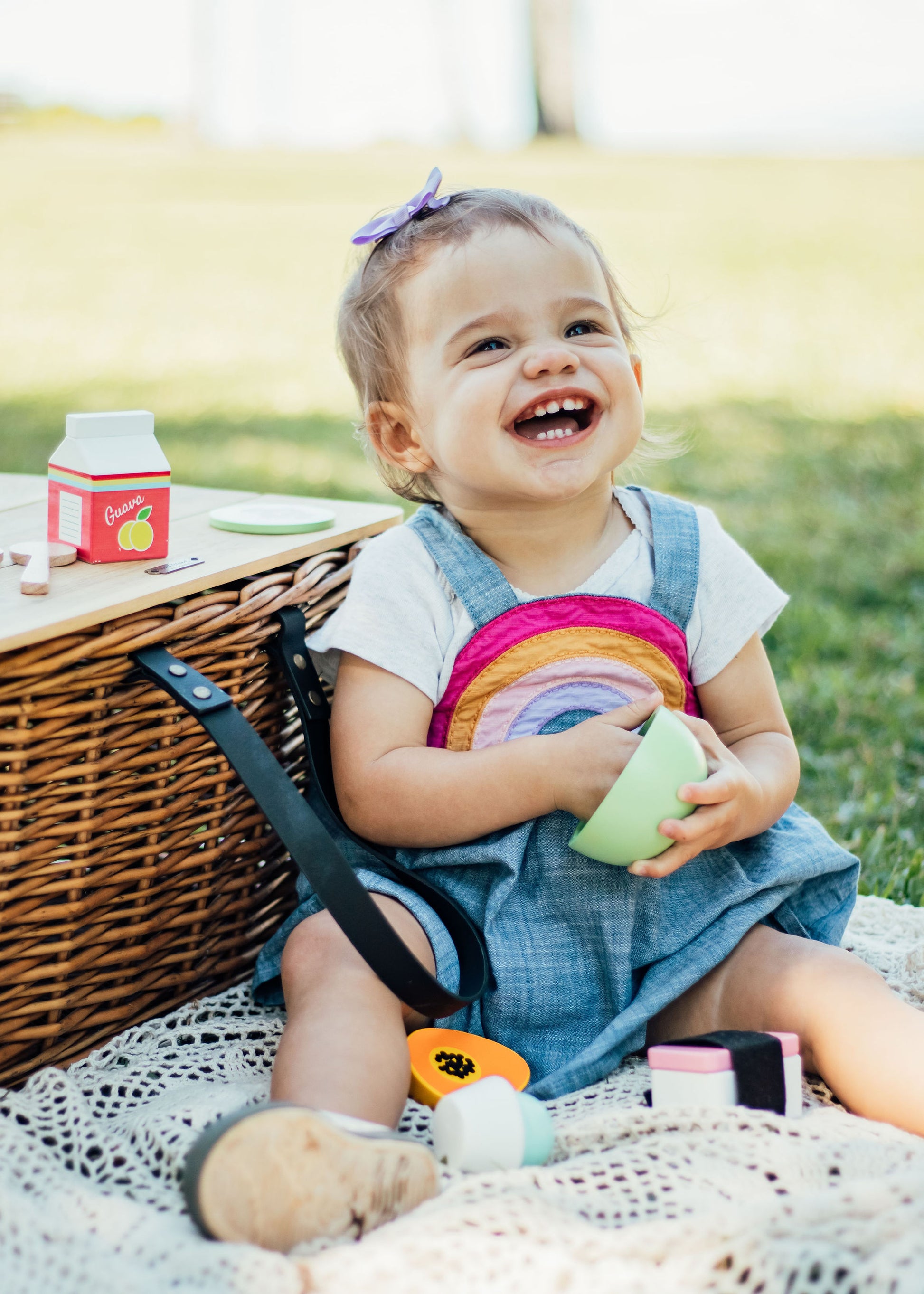 Baby sitting next to a basket playing with green wooden toy loco moco bowl