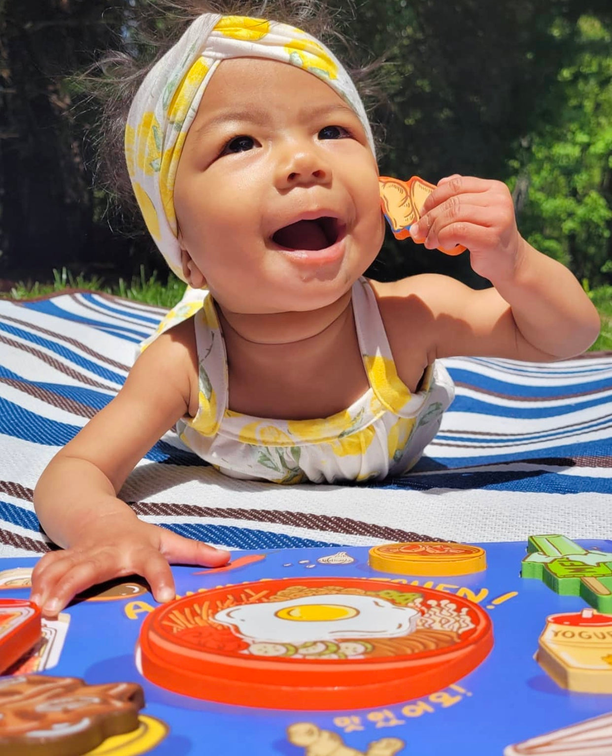 Baby holding mandoo shaped puzzle piece next to blue puzzle board