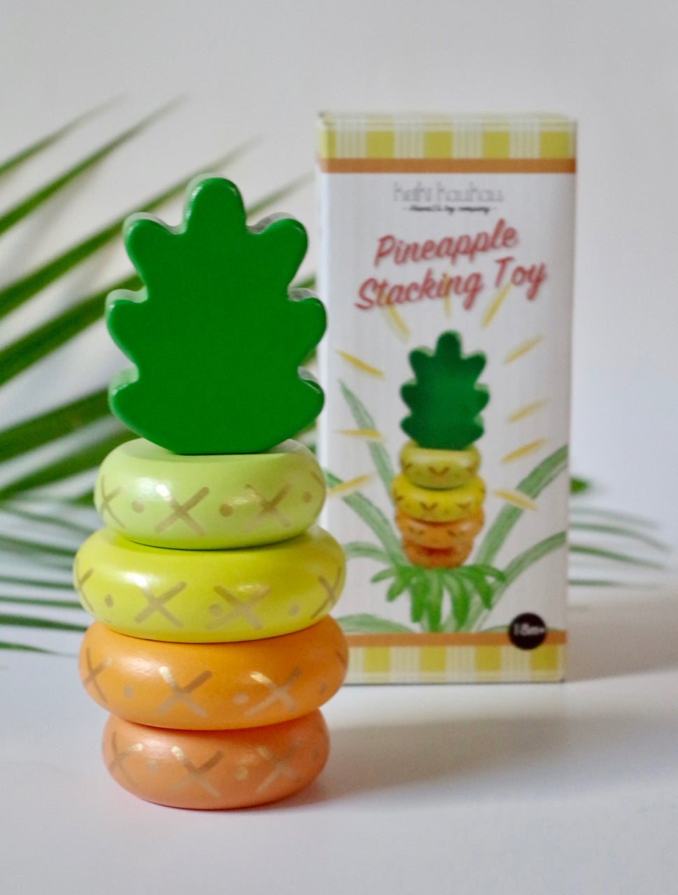 Yellow wooden pineapple stacking toy next to its box packaging