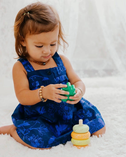 little girl playing with a piece of the yellow wooden pineapple stacking toy